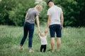 Happy family walking in meadow. Parents teaching little daughter Royalty Free Stock Photo