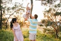 Happy family walking in the park. Mom, dad and daughter walk outdoors, parents holding the baby girl`s hands. Childhood, Royalty Free Stock Photo