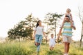 Happy family walking in the park. Mom, dad and daughter walk outdoors, parents holding the baby girl`s hands. Childhood, Royalty Free Stock Photo