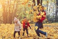 happy family walking in sunny park and throws orange maple leaves. mother with kids enjoying autumn weather outdoors Royalty Free Stock Photo