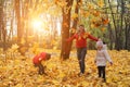 happy family walking in sunny park and throws orange maple leaves. mother with kids enjoying autumn weather outdoors Royalty Free Stock Photo