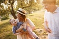 Happy family is walking togther in garden. Mother is playing with her son and carring him on hands. She is smiling Royalty Free Stock Photo