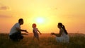 Happy family walks in park at sunset. Mom, dad and baby. Little daughter goes from mom to dad, hugs and kisses her Royalty Free Stock Photo