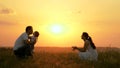 Happy family walks in park at sunset. Mom, dad and baby. Little daughter goes from mom to dad, hugs and kisses her Royalty Free Stock Photo