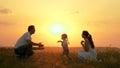 Happy family walks in park at sunset. Mom, dad and baby. Little daughter goes from mom to dad, hugs and kisses her Royalty Free Stock Photo