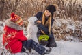 Happy family in warm clothing. Smiling mother and son making a snowman outdoor. The concept of winter activities Royalty Free Stock Photo