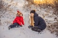 Happy family in warm clothing. Smiling mother and son making a snowman outdoor. The concept of winter activities Royalty Free Stock Photo