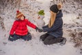 Happy family in warm clothing. Smiling mother and son making a snowman outdoor. The concept of winter activities Royalty Free Stock Photo