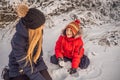 Happy family in warm clothing. Smiling mother and son making a snowman outdoor. The concept of winter activities Royalty Free Stock Photo