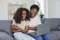 Happy family sitting on sofa at home, watching something funny on laptop and laughing Royalty Free Stock Photo