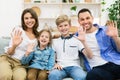 Happy Family Waving Hand Sitting Together On Couch At Home