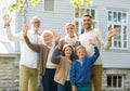 Happy family waving hands in front of house