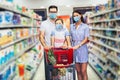 Family wearing face protective medical masks for protection from virus disease with shopping cart buying food at supermarket Royalty Free Stock Photo