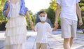 Happy family wearing the medical mask and walking in the park
