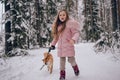 Happy family weekend - little cute girl in pink warm outwear walking having fun with red shiba inu dog in snowy white cold winter Royalty Free Stock Photo