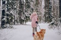 Happy family weekend - little cute girl in pink warm outwear walking having fun with red shiba inu dog in snowy white cold winter Royalty Free Stock Photo