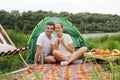 Happy family at weekend, wife and husband relaxing near the river, having picnic, enjoying coffee or tea, looking at camera with Royalty Free Stock Photo