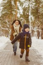 Happy family in winter clothing. Smiling son runs away from his mother outdoor Royalty Free Stock Photo