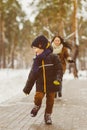 Happy family in winter clothing. Smiling son runs away from his mother outdoor Royalty Free Stock Photo