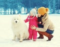 Happy family in winter day, mother and child walking with white Samoyed dog Royalty Free Stock Photo