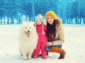 Happy family in winter day, smiling mother and child walking with white Samoyed dog Royalty Free Stock Photo