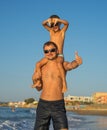 Happy family. Young beautiful father and his smiling son baby boy having fun on the beach of the sea, ocean , showing thumb up and Royalty Free Stock Photo