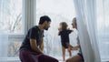 Happy family with young cute daughter sitting on windowsill playing and looking in window at home Royalty Free Stock Photo