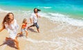 Happy family run together along sea surf on tropical beach Royalty Free Stock Photo