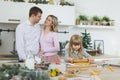 Happy family, young mother with baby, little girl making gingerbread cookie in decorated kitchen room with Christmas Royalty Free Stock Photo