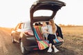 Happy family, a young mother with a child sitting in the trunk of a car, traveling Royalty Free Stock Photo