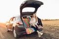 Happy family, a young mother with a child sitting in the trunk of a car, traveling Royalty Free Stock Photo