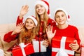 Happy family  a young mother and her little daughter and son  wearing santa claus hats  celebrate the New Year at home while Royalty Free Stock Photo