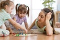 Happy family. Young mother playing ludo boardgame with her daughters while spending time together at home.