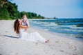 Happy family. Young mother throws up baby in the sky, on sunny day on the beach. Royalty Free Stock Photo