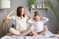 Happy family young mum and cute little child daughter doing gymnastic exercise in bedroom, funny kid and mother having fun on bed Royalty Free Stock Photo