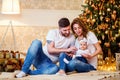Happy family. Young parents hugging little baby girl while sitting near Christmas tree on the floor Royalty Free Stock Photo