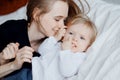 Happy family, young woman mother kisses baby in bed
