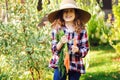 Happy farmer child girl picking fresh home growth carrot harvest from own garden Royalty Free Stock Photo