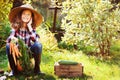 Happy farmer child girl sitting with autumn harvest in the garden