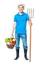 Happy farmer with forks and a crop of vegetables on a white