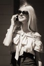 Happy fashion blond woman in sunglasses calling on mobile phone Royalty Free Stock Photo