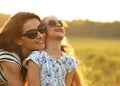 Happy fashion kid girl embracing her mother in trendy sunglasses