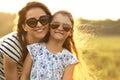 Happy fashion kid girl embracing her mother in trendy sunglasses