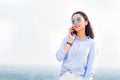 Happy fashionable woman with glasses talking on the phone and smiling at the background of nature, sky. Business lady is successfu Royalty Free Stock Photo