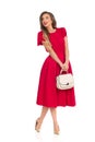 Happy Fashionable Woman In Red Dress, Gold High Heels And Beige Purse Is Looking Away Royalty Free Stock Photo