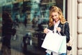 Happy fashionable woman with shopping bags standing at shop window. Lifestyle concept. Positive emotions. Girl enjoying purchases Royalty Free Stock Photo