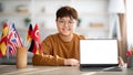 Happy chinese teenager boy showing laptop with blank screen