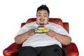 Happy fat man holds donuts on the armchair Royalty Free Stock Photo