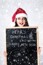 Happy fat Santa girl. A model in a santa hat. XXL a woman celebrating Christmas and a new year. Holds a plaque with the New