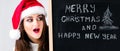 Happy fat Santa girl. A model in a santa hat. XXL a woman celebrating Christmas and a new year. Holds a plaque with the New